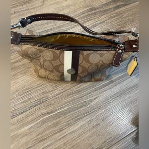 Coach brown monogram mini bag with solid yellow lining.